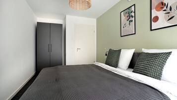 Un dormitorio con cama, armario y dos cuadros en la pared.