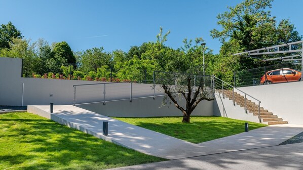A modern architectural structure with a staircase, a tree, and a car parked on the upper level. - Luxury Villa Callista with a heated swimming pool and gym (Ružići)