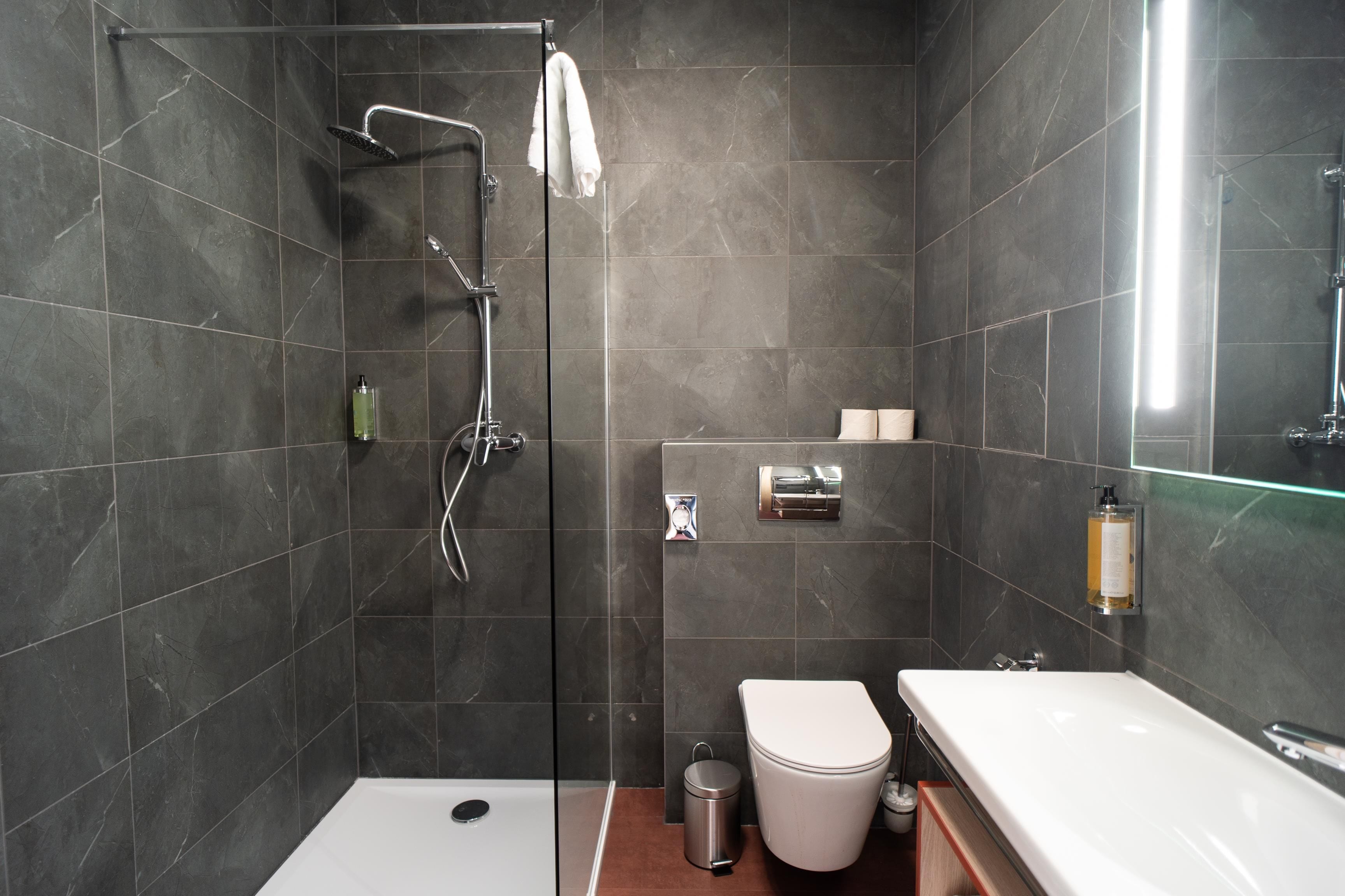 A modern bathroom with a glass-enclosed shower, a white toilet, and a sink.