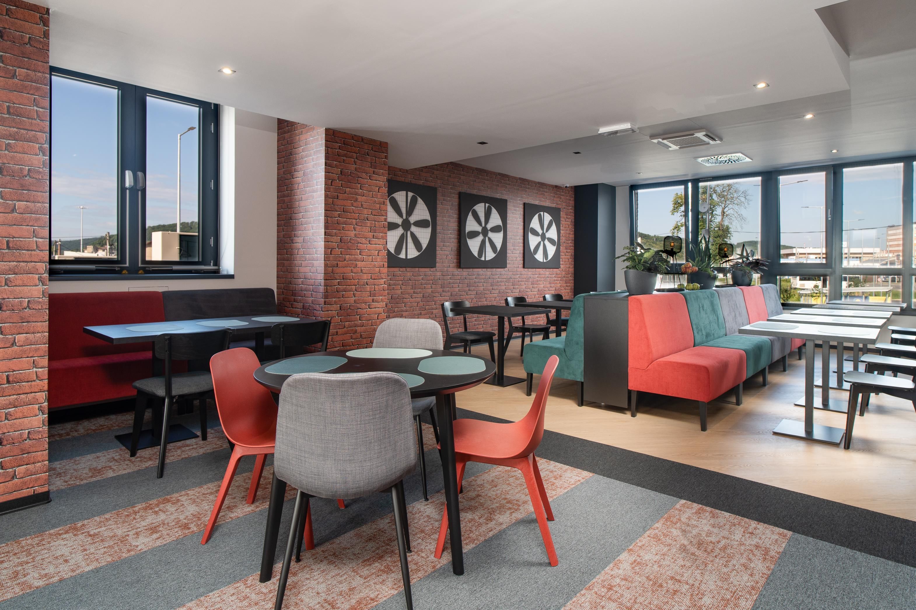 Un espace de détente moderne avec des murs en briques, de grandes fenêtres et divers types de sièges, notamment des tables, des chaises et un canapé.