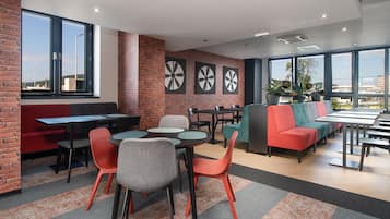 Un espace de détente moderne avec des murs en briques, de grandes fenêtres et divers types de sièges, notamment des tables, des chaises et un canapé.