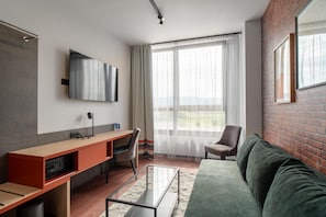 Una sala de estar moderna con un sofá, un escritorio, una silla y un televisor montado en la pared.