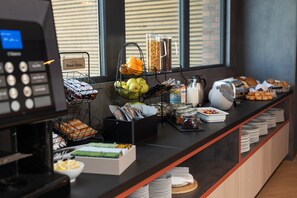 Montaje de bufé con diferentes opciones de comida y una máquina de café.