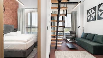 A modern hotel room with a bed, a sofa, a desk, and a staircase.