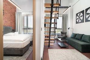 Una habitación de hotel moderna con una cama, un sofá, un escritorio y una escalera.