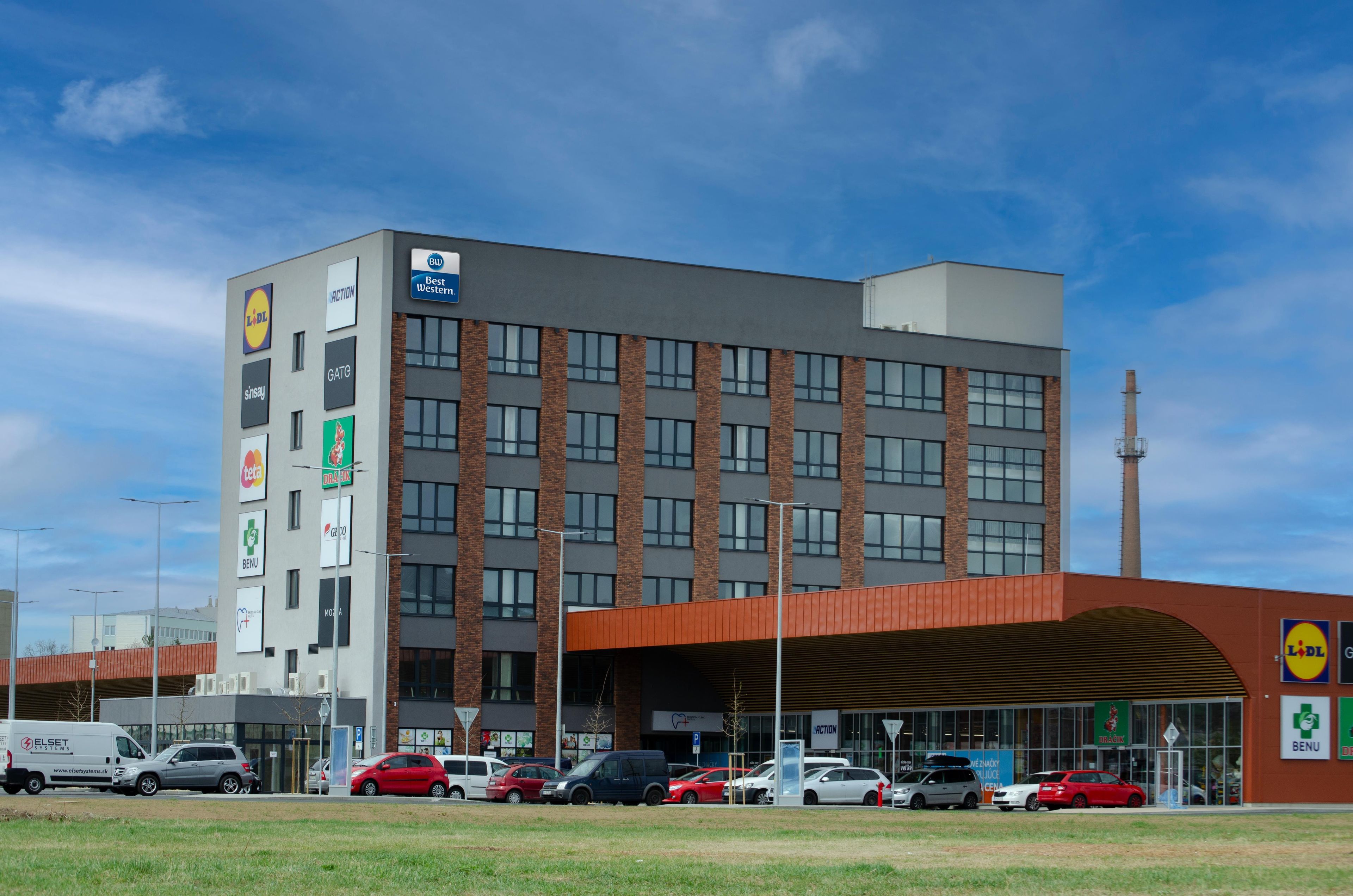 Un edificio comercial de varios pisos con diversas tiendas minoristas en la planta baja, incluyendo una farmacia y un local de comida.