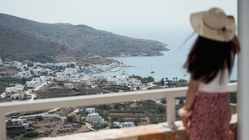 A coastal town with white buildings, a view of the sea, and a person in a hat and skirt.