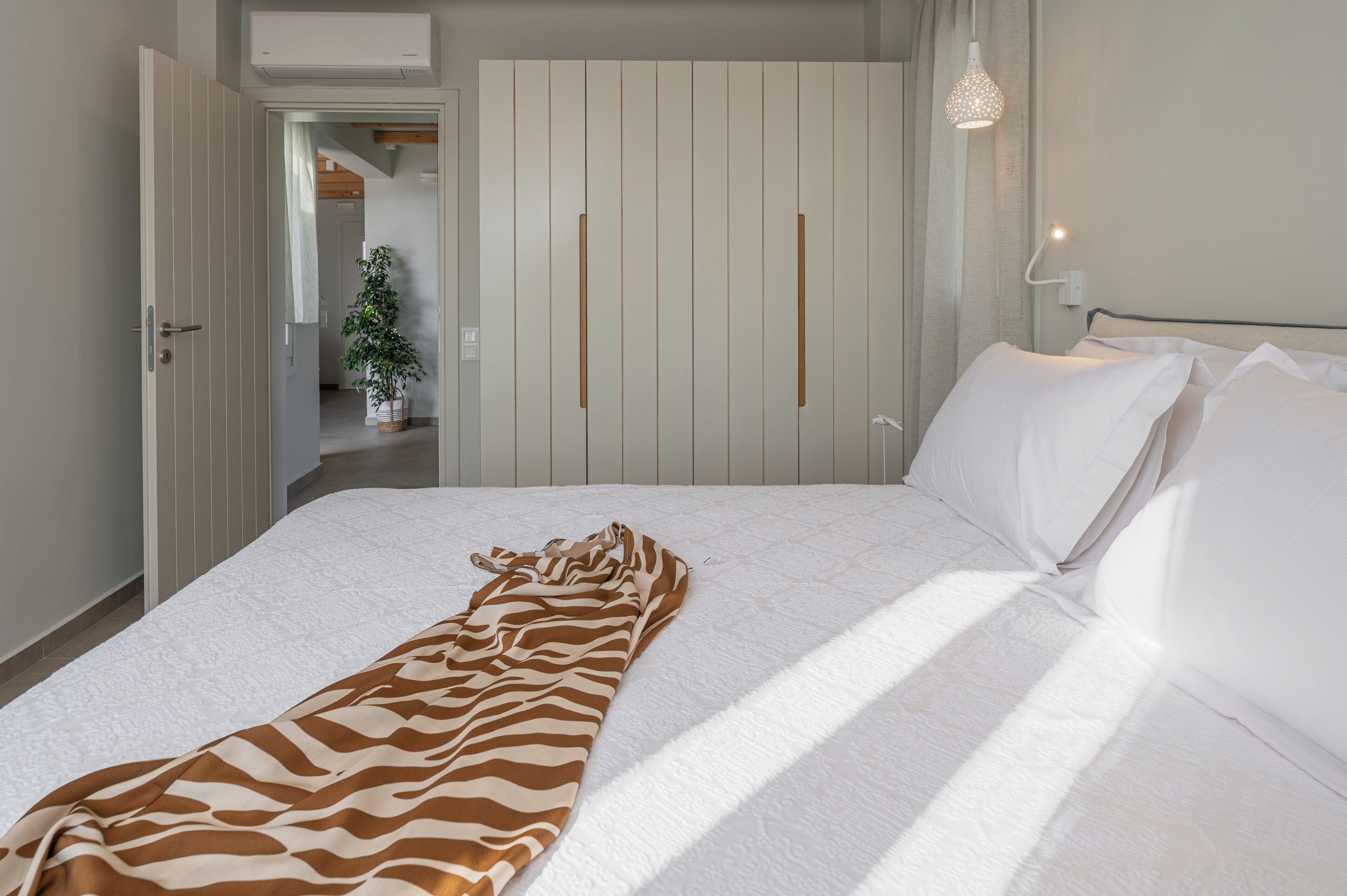 Un dormitorio con cama, manta de estampado de cebra, armario y lámpara colgante.