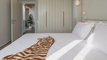 Un dormitorio con cama, manta de estampado de cebra, armario y lámpara colgante.