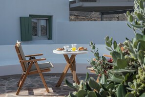 Une table avec une boisson, une assiette de nourriture et une chaise, dans une pièce avec une fenêtre et des plantes.