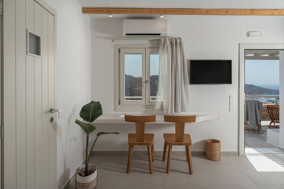 Une chambre moderne avec un plafond en bois, une fenêtre avec des rideaux, un téléviseur à écran plat et une vue sur l’extérieur.