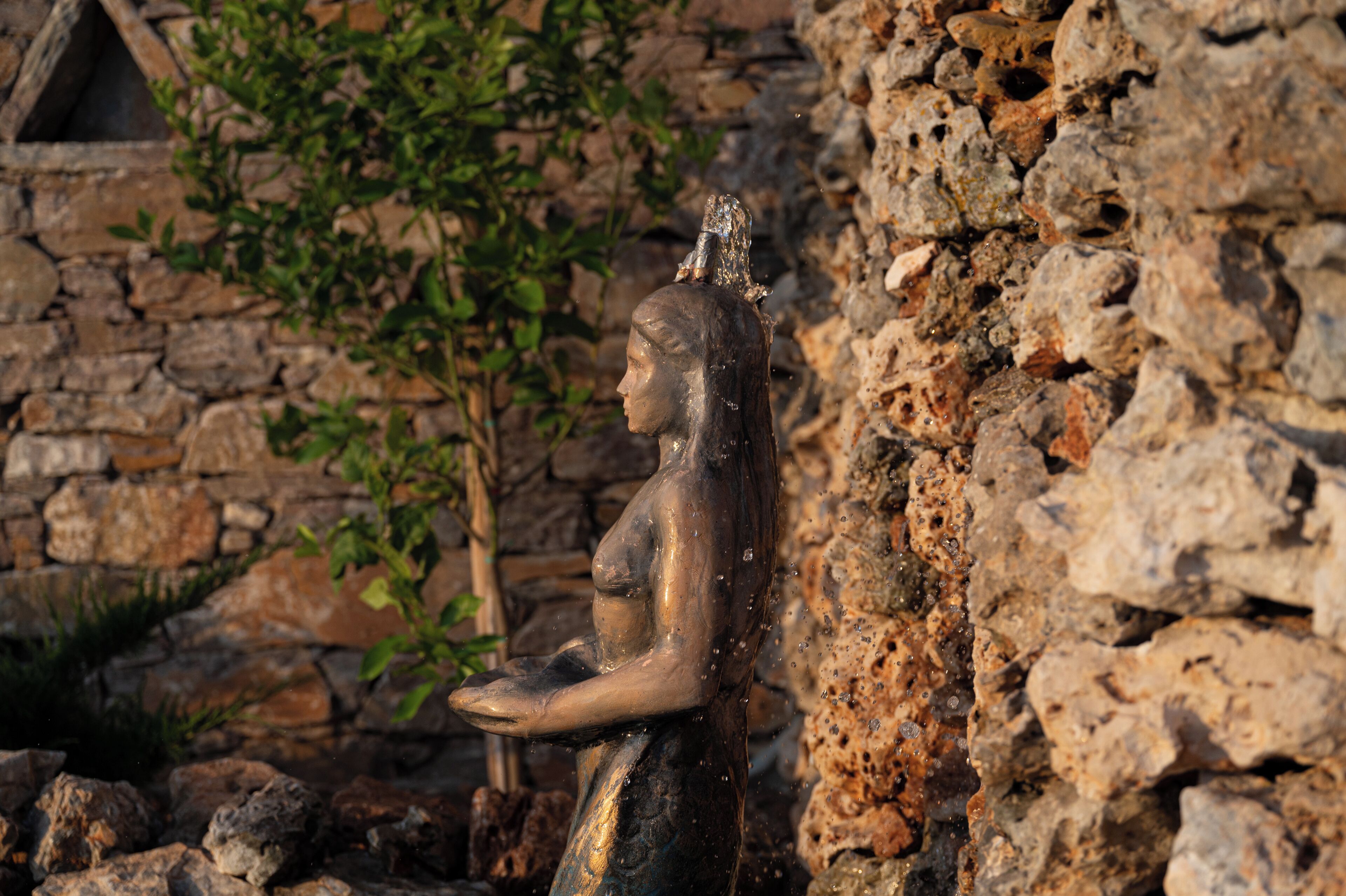 A stone wall with a statue of a seated figure.