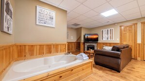 Een gezellige kamer met een houten badkuip, een bank, een open haard en inspirerende muurdecoratie.