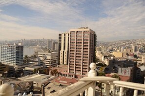 A cityscape with a prominent high-rise building in the center, surrounded by other buildings and a body of water in the background. - Hotel Brighton (Valparaiso)