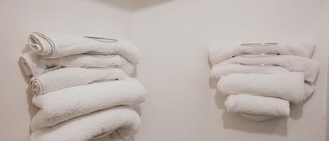 Two stacks of white towels on a wall, each with a metal bar.