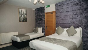 Une chambre d’hôtel avec deux lits, un radiateur, un tableau et une porte en bois.