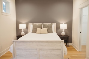 Un dormitorio con cama, dos mesitas de noche con lámparas, una ventana y una puerta.