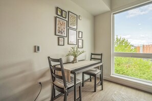 A dining area with a table and chairs, a vase with flowers, and framed pictures on the wall. - Top Floor Apt -minutes walk to Downtown Redmond/Marymoor in the heart of Redmond (Redmond)