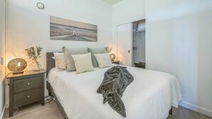 Ein ordentlich eingerichtetes Schlafzimmer mit Bett, Nachttischlampen, einem Spiegel und einem Bild an der Wand.