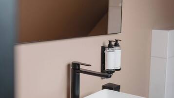 A modern bathroom with a white sink, a large mirror, and two black faucets.