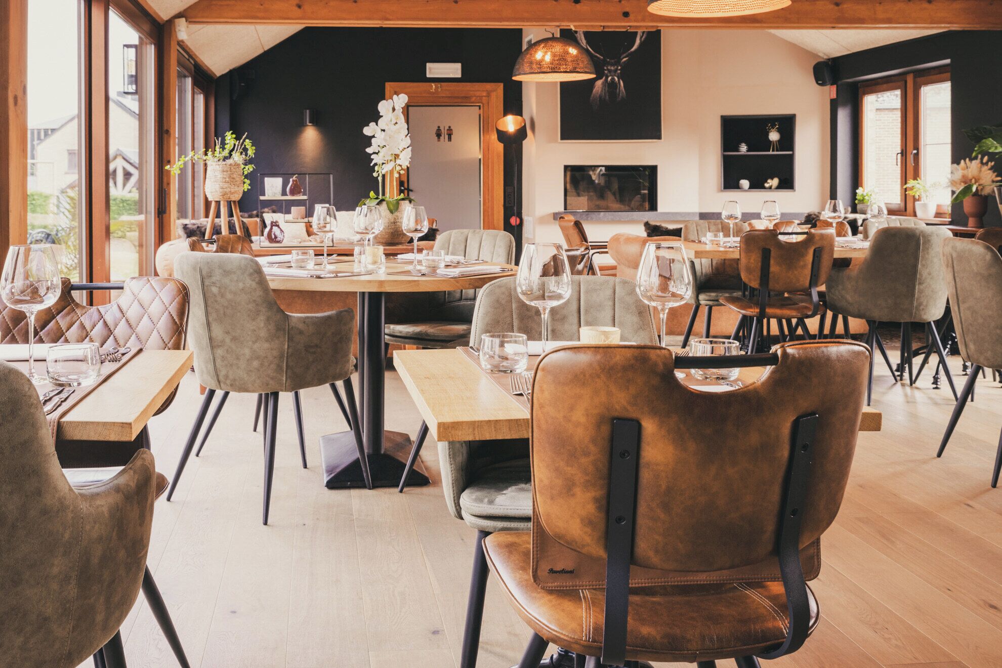 A restaurant with wooden tables and chairs, large windows, and a modern interior design.