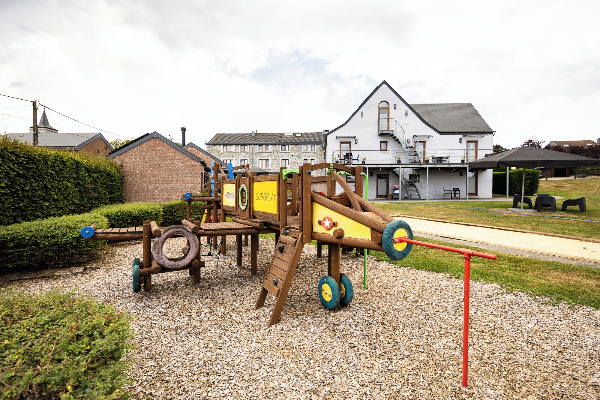 A playground with a wooden structure, tire swings, and a slide.