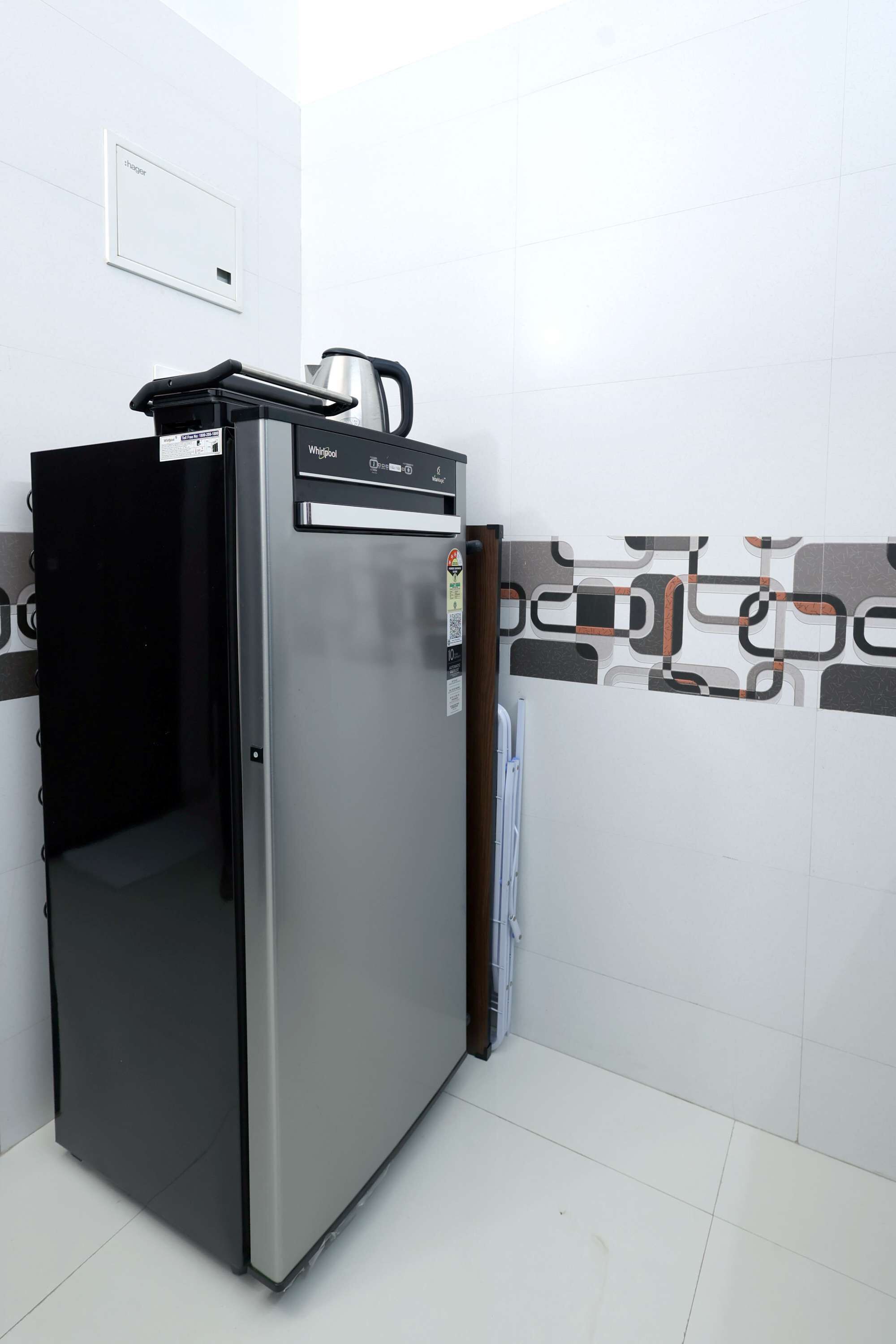 A compact refrigerator with a digital display, a kettle on top, and a small shelf.