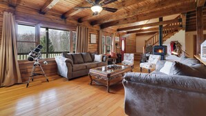 A cozy living room with wooden beams, a ceiling fan, a fireplace, and a telescope. - Secluded & Tranquil Retreat for 14 in the Poconos – Firepit/Games/Stargazing+ (Lake Ariel)