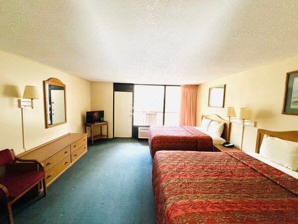 Une chambre d’hôtel avec deux lits, une commode, une télévision et un balcon.