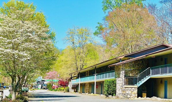 A motel with a stone facade, a covered porch, and a sign indicating an ice machine. - Newfound Lodge on the river (Cherokee)
