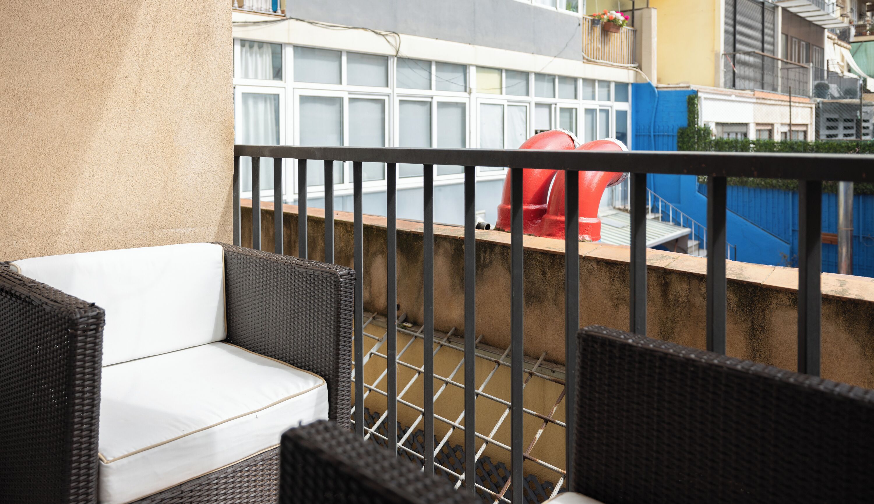 A balcony with wicker furniture and a metal railing.