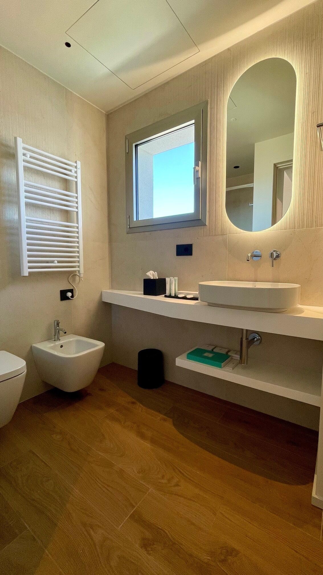 A modern bathroom with a bidet, a toilet, a sink, and a mirror.