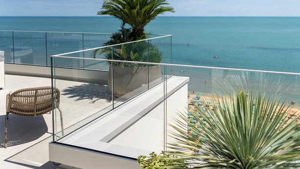 A rooftop terrace with a clear view of the ocean, a wicker chair, and potted plants. - Opera Suite hotel Pesaro (Pesaro)