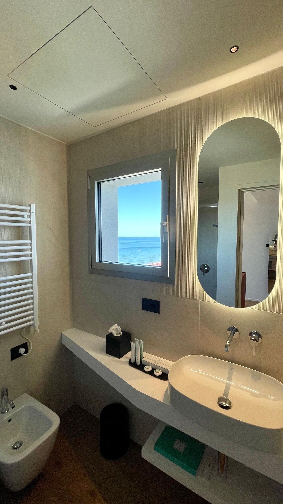 A modern bathroom with a large window, a built-in sink, and a bidet.
