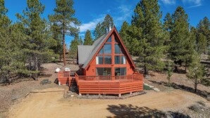 A cabin with a red exterior, large windows, and a deck area. - Charming Updated 3-bedroom Chalet with Deck; Small dogs welcome! (Angel Fire)