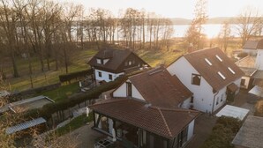 A residential area with houses, a patio, and a view of a body of water. - Time by the lake. Studio Rosengarten – Terrace & Panoramic Views: More Than Just a Vacation (Bad Saarow)