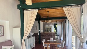A cozy room with a dining table, chairs, a white cabinet, and a brick fireplace. - Time by the lake. Studio Rosengarten – Terrace & Panoramic Views: More Than Just a Vacation (Bad Saarow)
