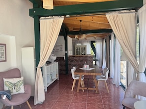 Una habitación acogedora con una mesa de comedor, sillas, un armario blanco y una chimenea de ladrillo.