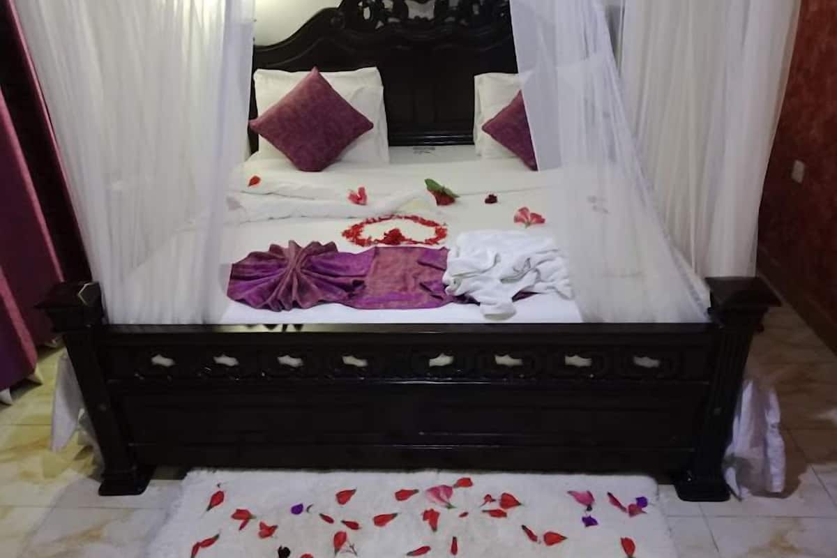 A bed with a canopy, pillows, and a floral arrangement on the bed.