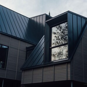 A modern building with a sloped roof and a large window. - The Pioneer | BESIDE's very first cabin (Lanaudière)