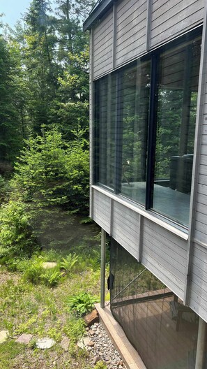 A modern building with large windows, surrounded by dense forest. - The Pioneer | BESIDE's very first cabin (Lanaudière)