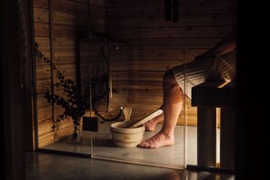 A wooden cabin interior with a sauna, a wooden bench, and a small plant. - The Shoal (Lanaudière)