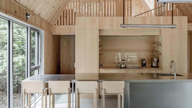 Una cocina moderna con detalles de madera, una barra y un espacio de descanso con un sofá gris.