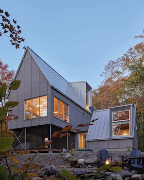 A modern house with a sloped roof, large windows, and a stone foundation.