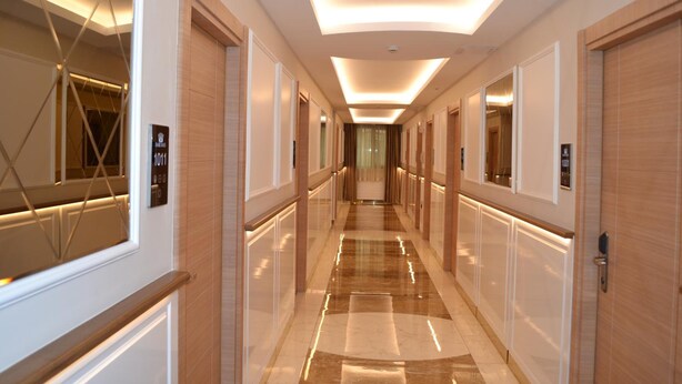 A modern hotel corridor with a polished floor, wooden paneling, and illuminated ceiling panels. - Nuans Pansiyon (Istanbul)