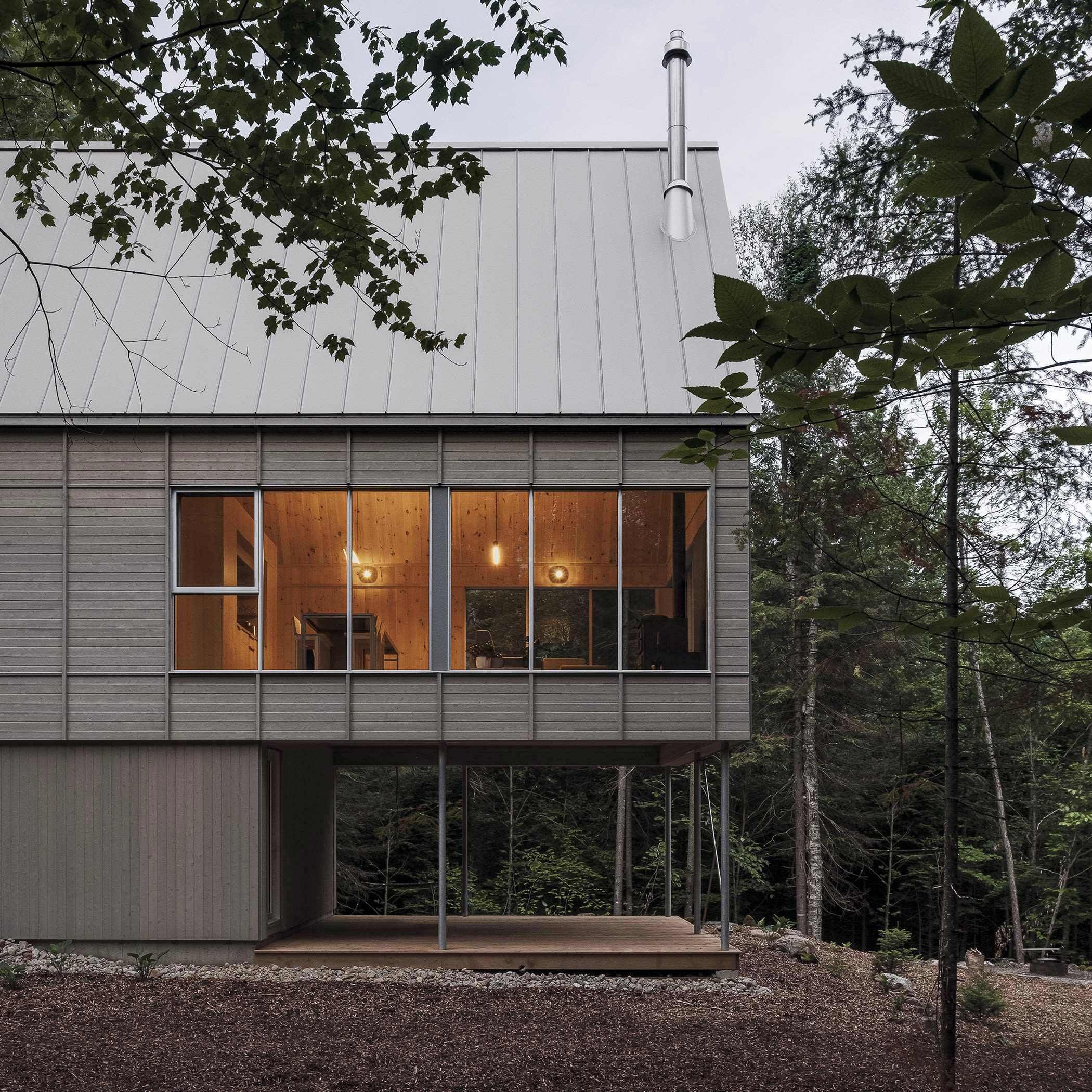 Una casa moderna con ventanas amplias, una chimenea y una terraza.