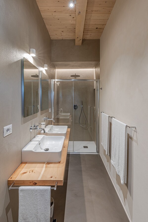 Une salle de bain moderne avec deux lavabos, une douche en verre et des éléments décoratifs en bois.