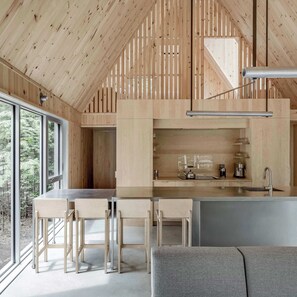 Una cocina moderna con detalles de madera, una barra y un espacio de descanso con un sof á gris.