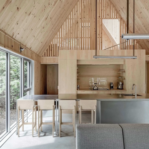 A modern kitchen with a wooden interior, a bar area, and a seating space with a grey sofa.