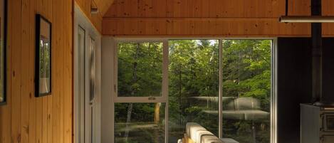 A wooden interior with a high ceiling, large windows, and a view of trees.